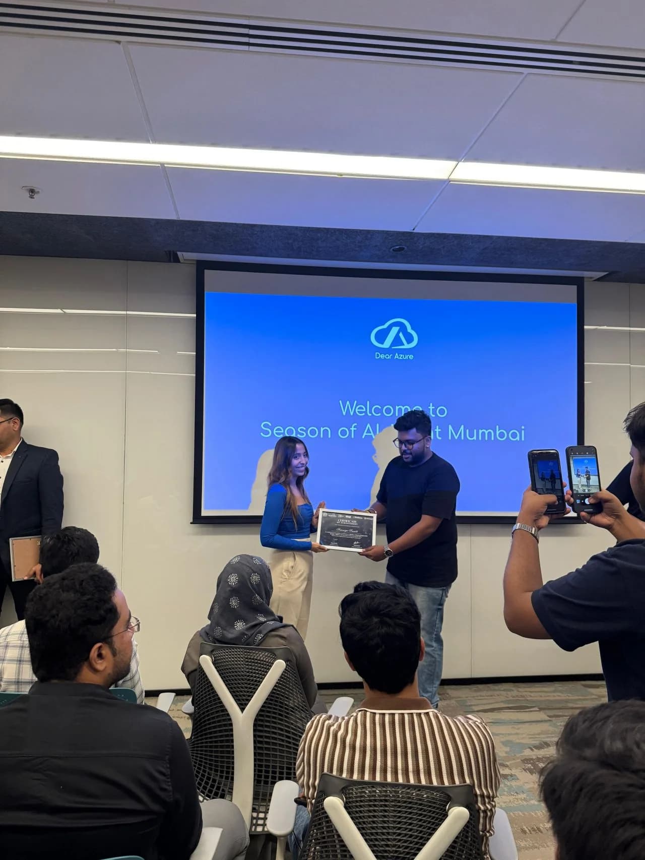 Saumya Smriti receiving an event certificate in front of the Season of AI screen.